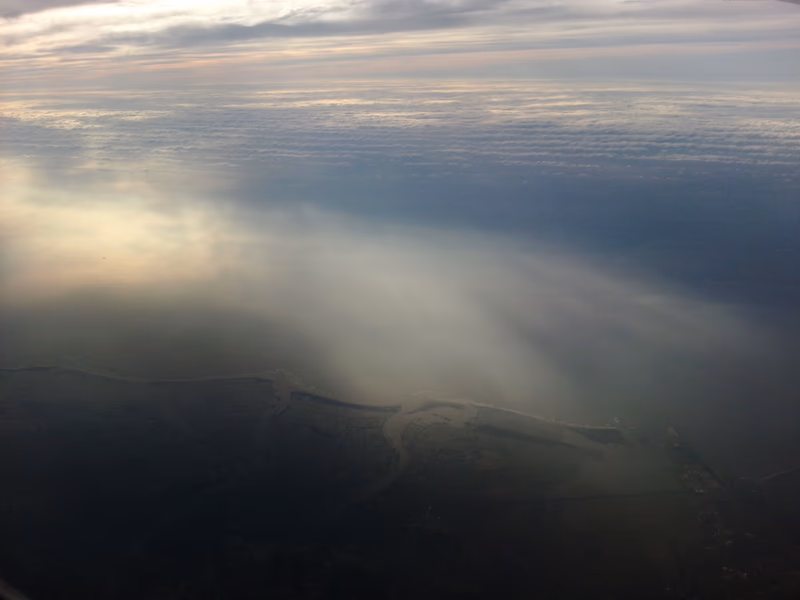 Aerial view of a body of water with clouds and land in the background.